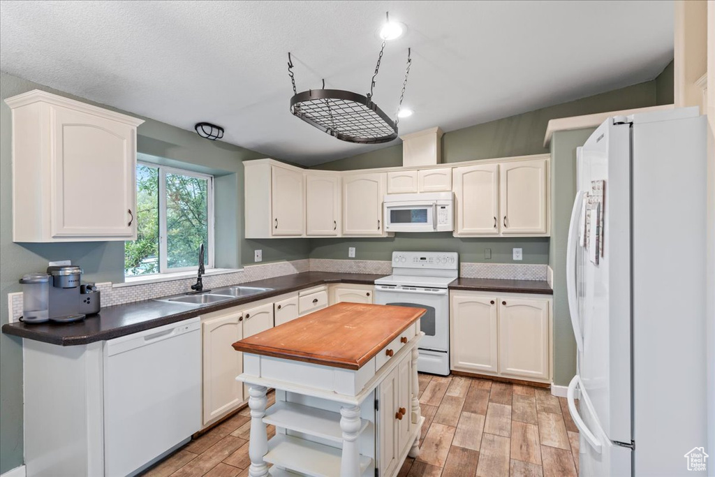 Kitchen featuring light hardwood / wood-style flooring, white cabinetry, sink, and white appliances