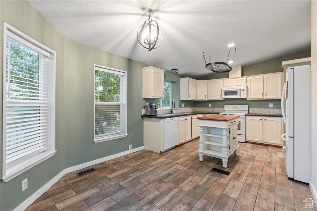 Kitchen featuring white appliances, pendant lighting, light hardwood / wood-style flooring, and plenty of natural light