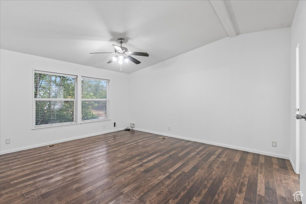 Unfurnished room featuring dark wood-type flooring, ceiling fan, and vaulted ceiling with beams