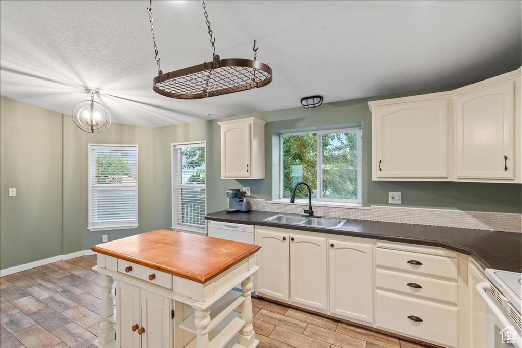 Kitchen with sink, light hardwood / wood-style flooring, white cabinetry, and a healthy amount of sunlight