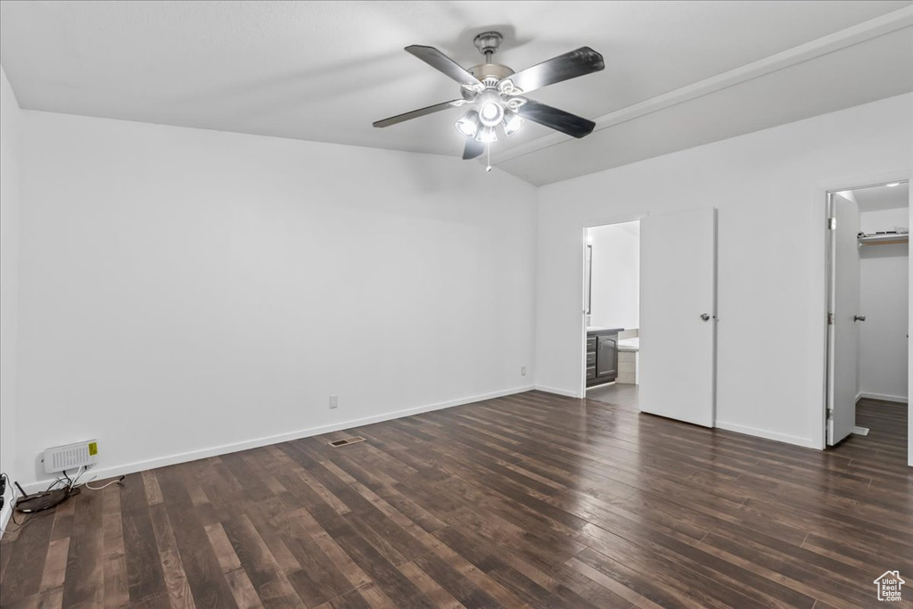 Unfurnished bedroom with connected bathroom, dark hardwood / wood-style floors, a closet, a spacious closet, and ceiling fan