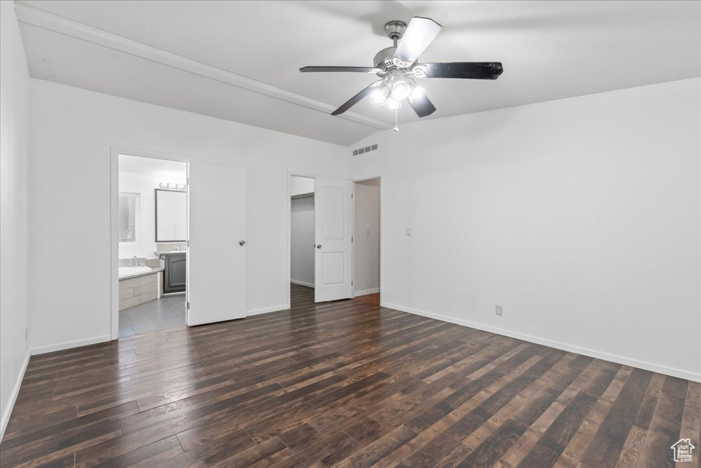 Unfurnished bedroom featuring dark hardwood / wood-style floors, ensuite bath, vaulted ceiling, and ceiling fan