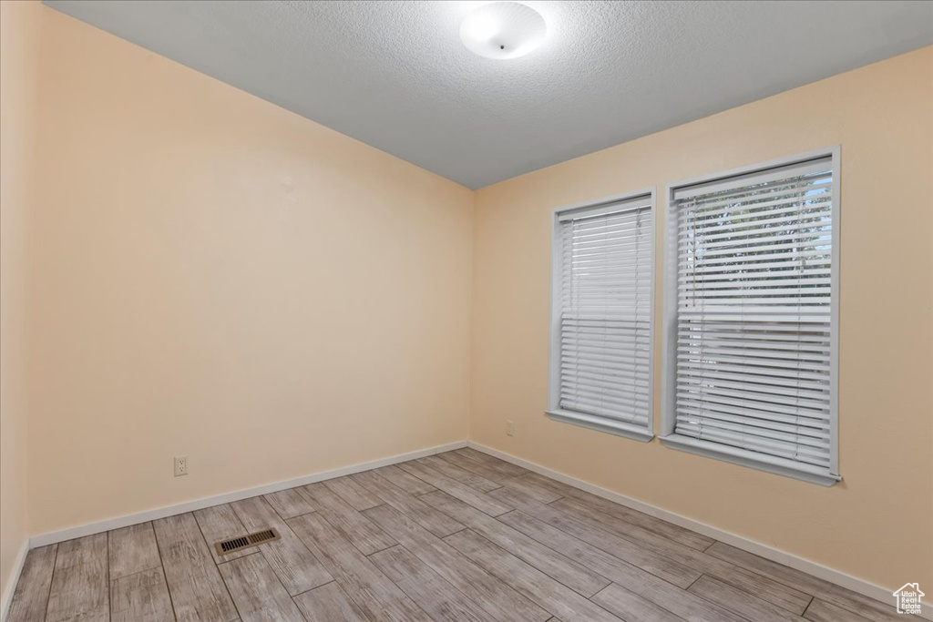 Unfurnished room with a textured ceiling and light wood-type flooring