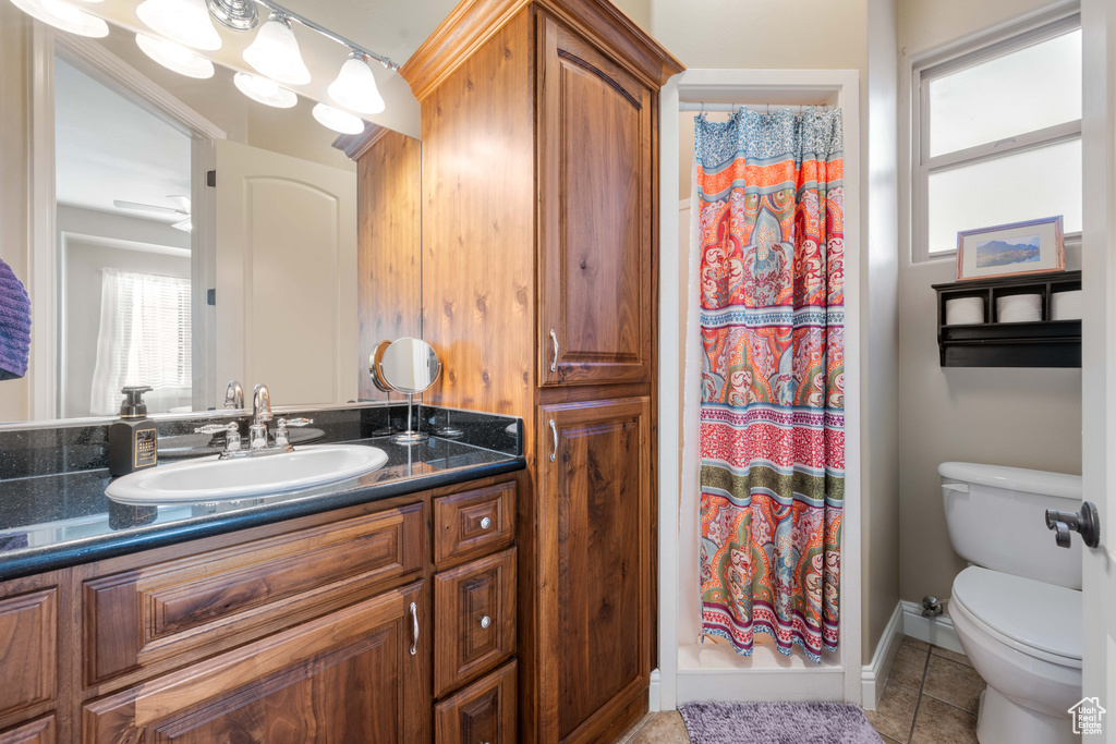 Bathroom featuring vanity, curtained shower, toilet, and tile patterned flooring