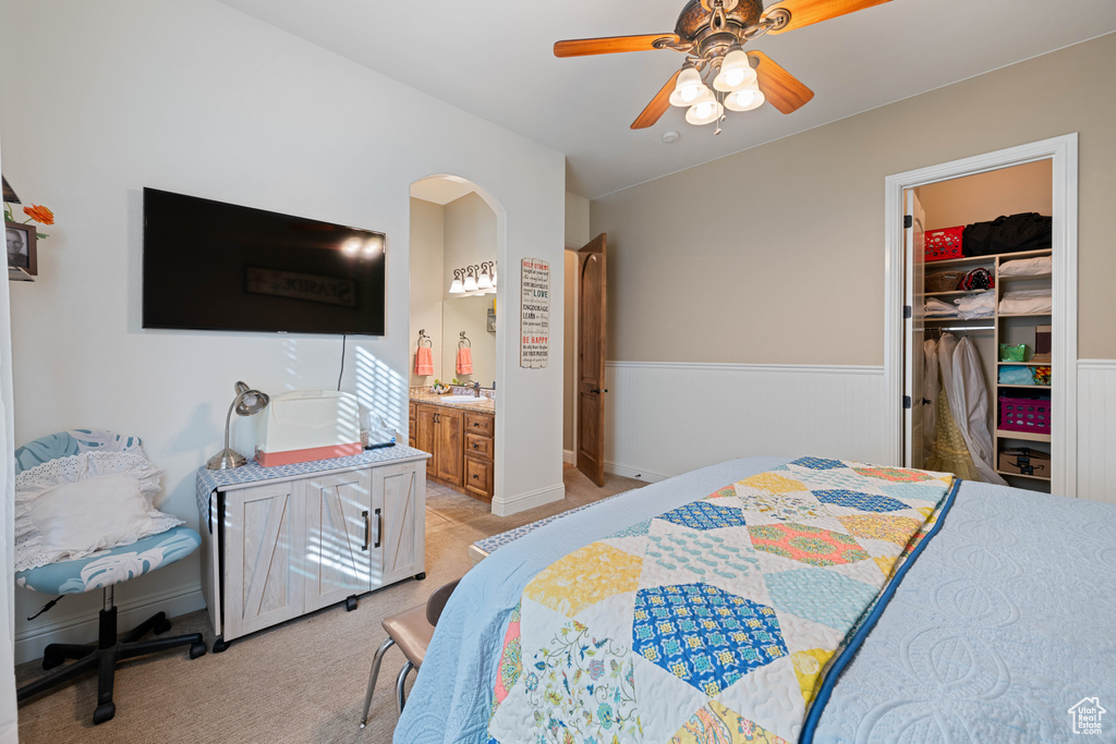 Bedroom with a walk in closet, ensuite bath, a closet, ceiling fan, and light colored carpet