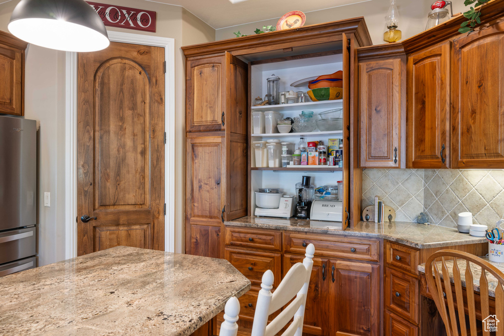 Kitchen featuring light stone counters, tasteful backsplash, and stainless steel refrigerator