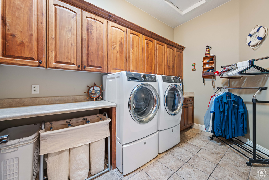 Washroom with light tile patterned floors, cabinets, and separate washer and dryer