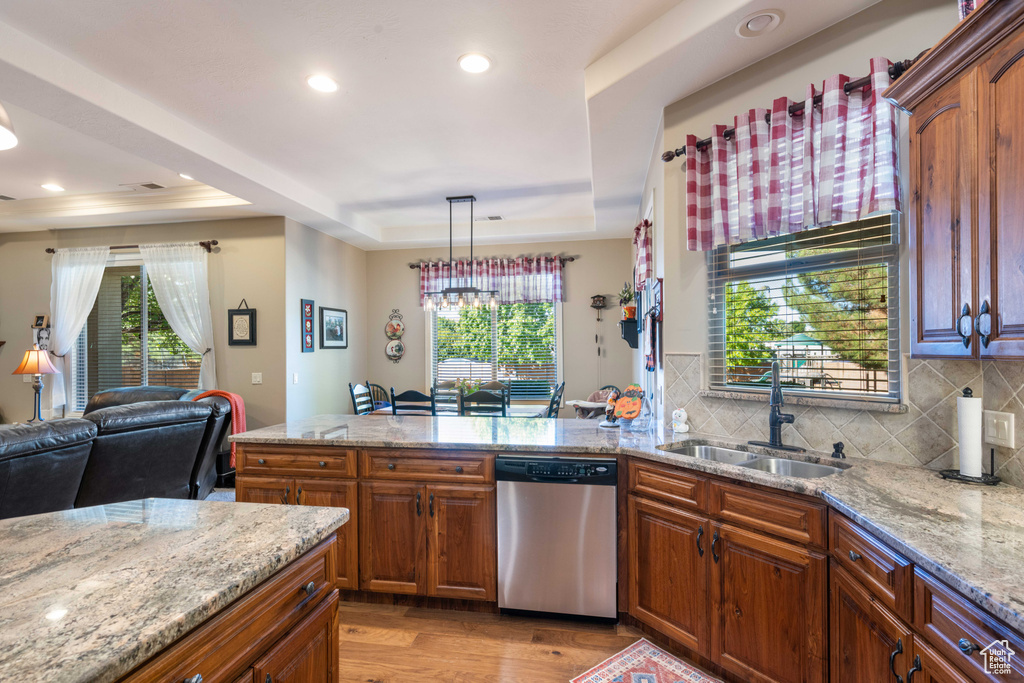 Kitchen with a tray ceiling, dishwasher, light wood-type flooring, and a healthy amount of sunlight