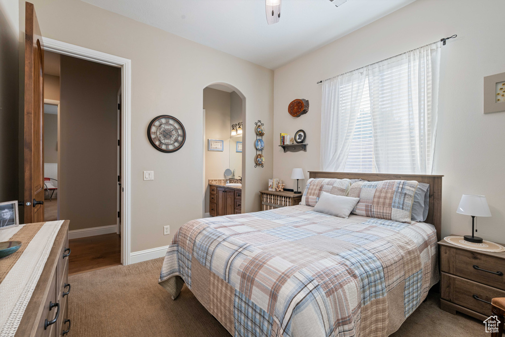 Bedroom with connected bathroom, light colored carpet, and ceiling fan