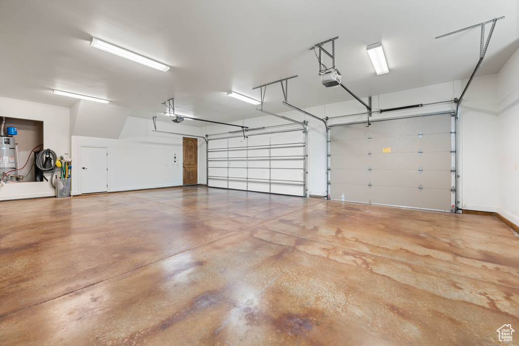 Garage featuring a garage door opener and secured water heater