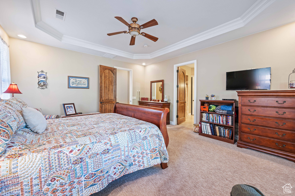 Carpeted bedroom featuring ornamental molding, a raised ceiling, and ceiling fan