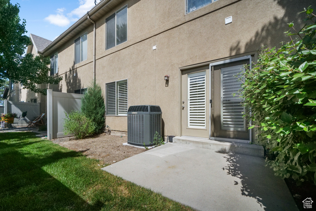 View of exterior entry featuring a patio, cooling unit, and a yard