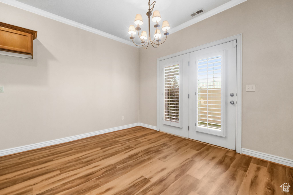 Unfurnished dining area featuring ornamental molding, light hardwood / wood-style flooring, and an inviting chandelier