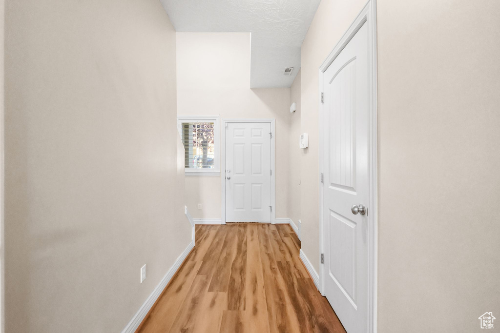 Corridor with a textured ceiling and light hardwood / wood-style flooring