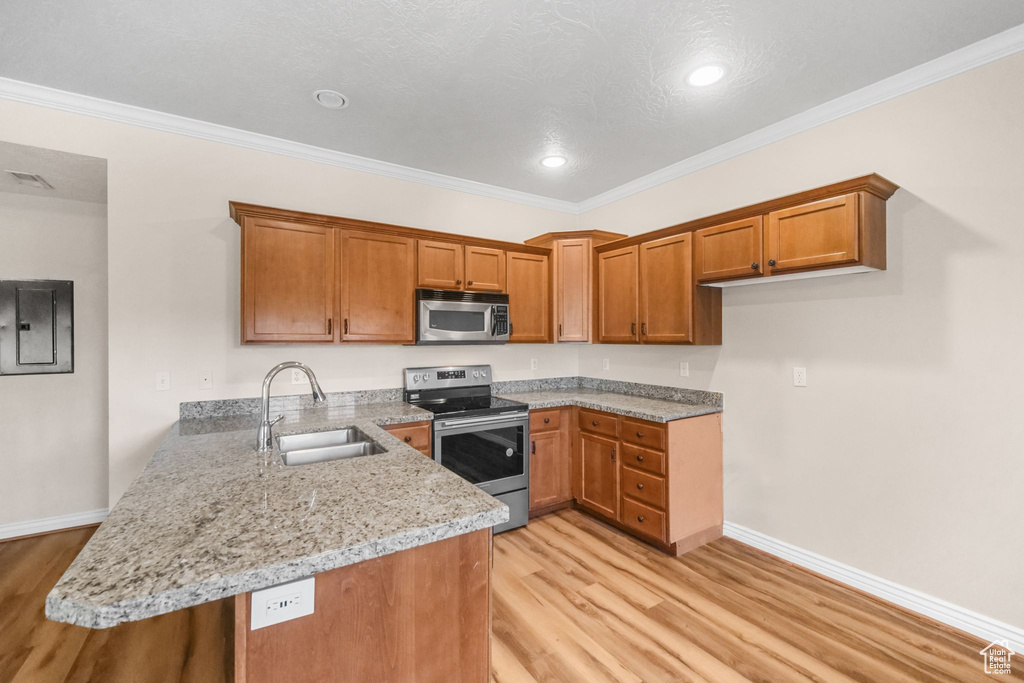 Kitchen featuring stainless steel appliances, light stone countertops, sink, and kitchen peninsula