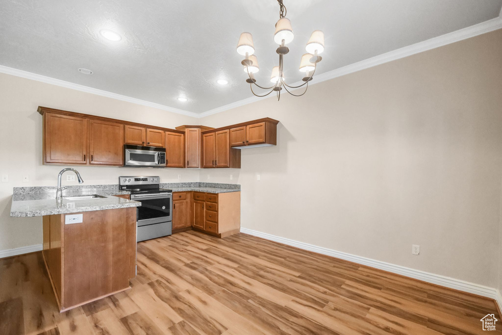 Kitchen featuring ornamental molding, hanging light fixtures, stainless steel appliances, and light hardwood / wood-style floors