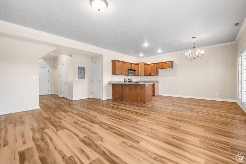 Kitchen with light hardwood / wood-style flooring, decorative light fixtures, a notable chandelier, and crown molding