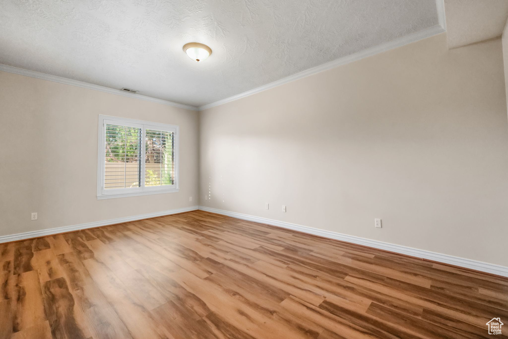 Empty room featuring crown molding and hardwood / wood-style floors