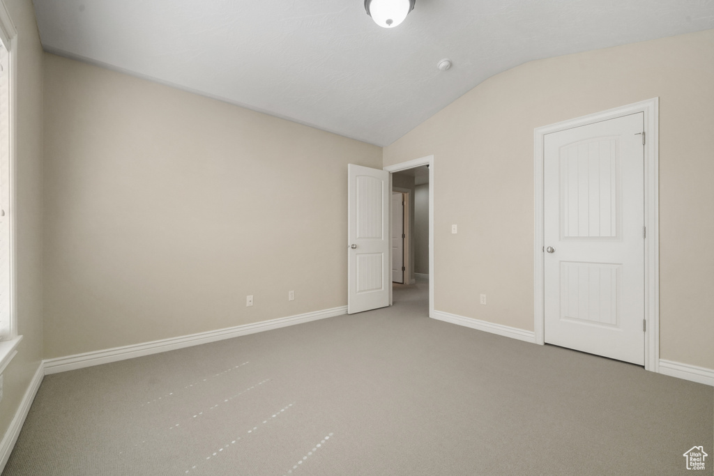 Unfurnished bedroom featuring carpet and lofted ceiling