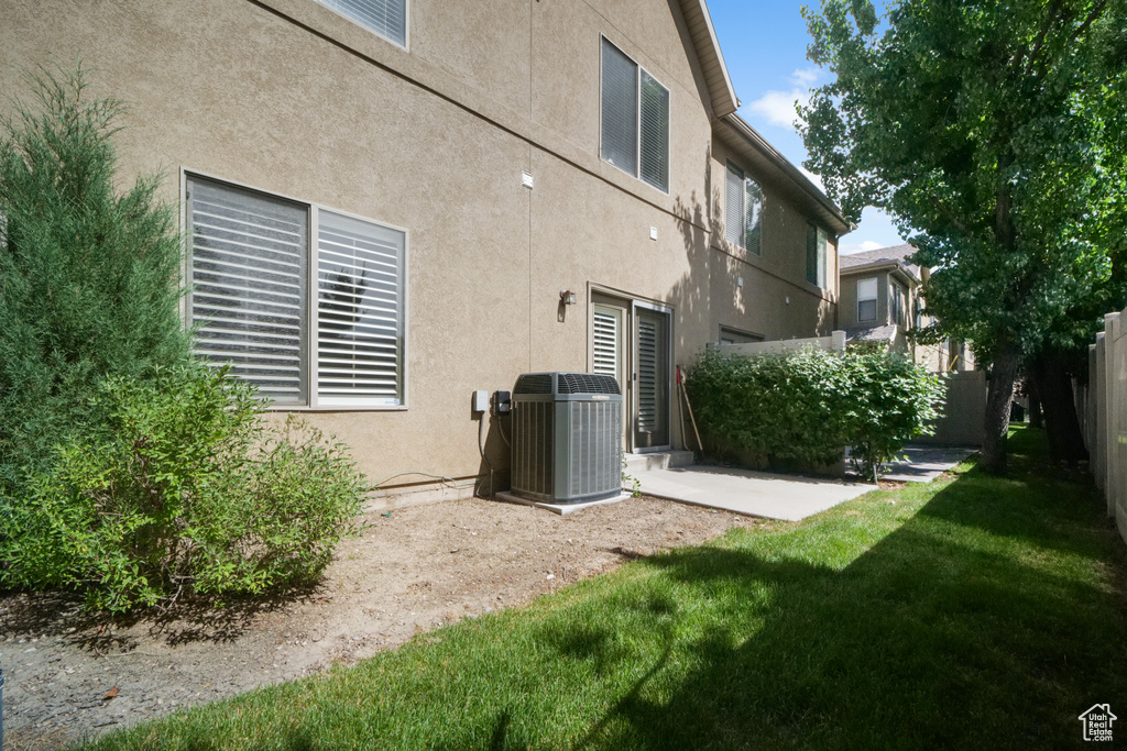 Rear view of house with central air condition unit and a yard