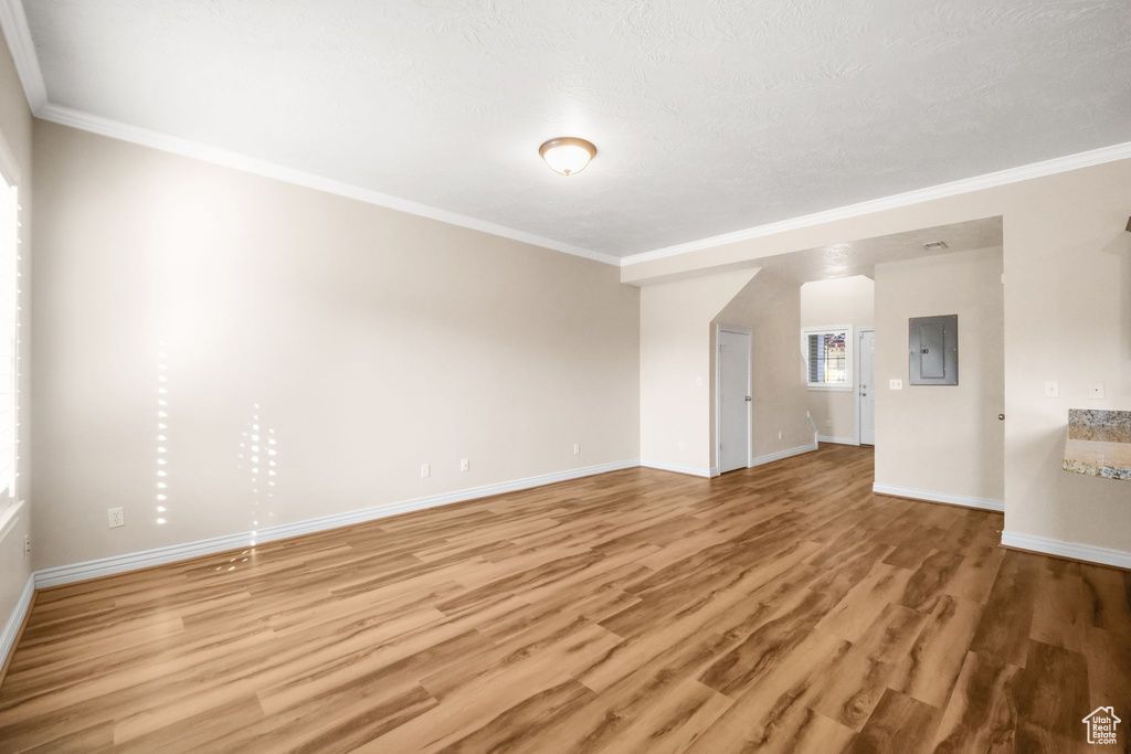 Unfurnished living room with electric panel, crown molding, wood-type flooring, and a textured ceiling