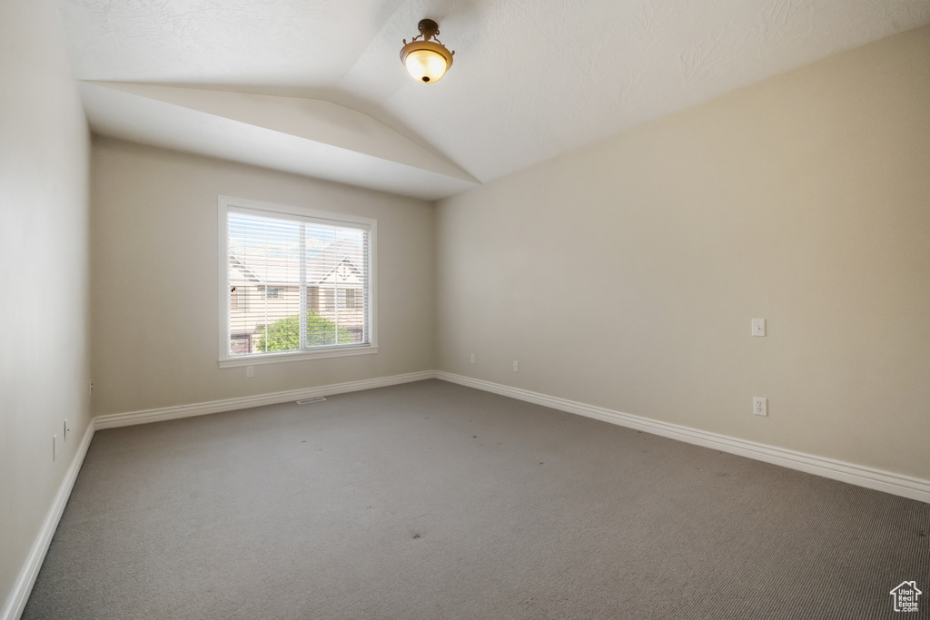 Carpeted empty room with vaulted ceiling