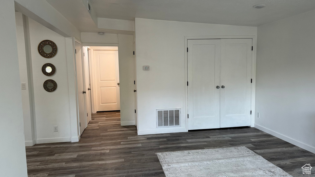 Unfurnished bedroom featuring a closet, vaulted ceiling, and dark hardwood / wood-style flooring