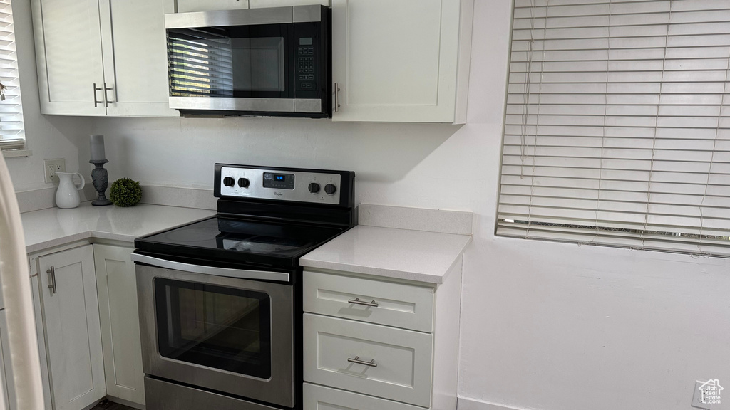 Kitchen featuring white cabinetry and appliances with stainless steel finishes