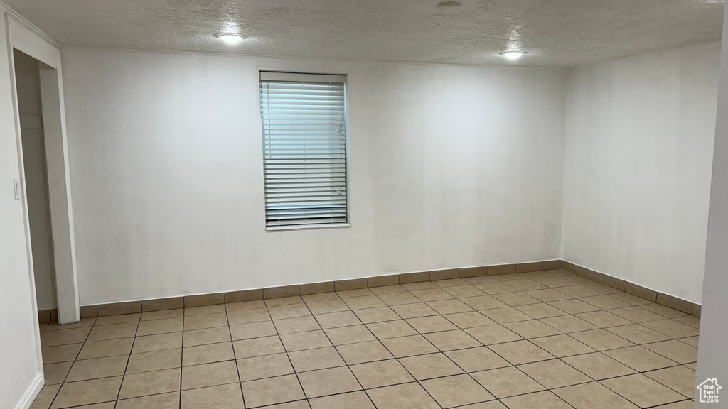 Empty room featuring a textured ceiling and light tile patterned floors