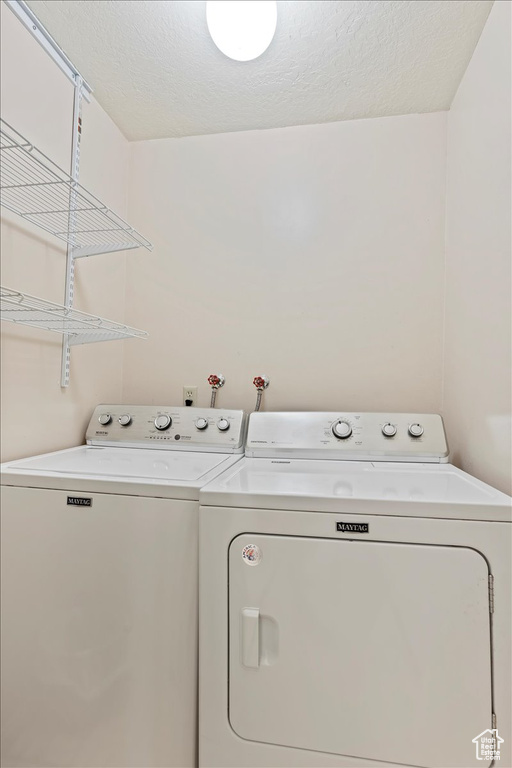 Clothes washing area with washer and dryer and a textured ceiling