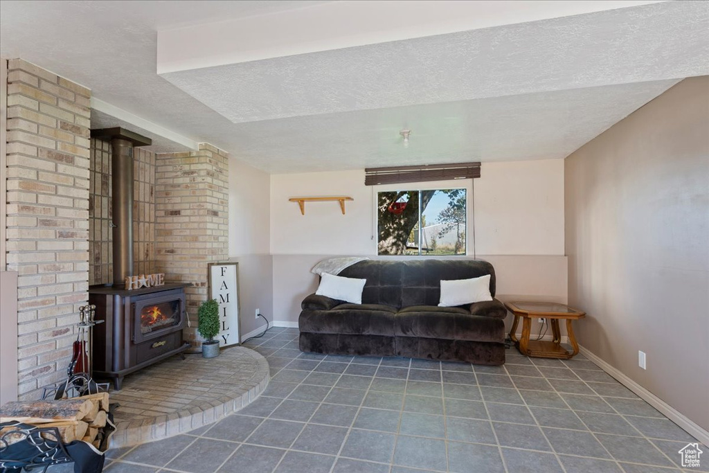 Sitting room with dark tile patterned floors, a textured ceiling, and a wood stove