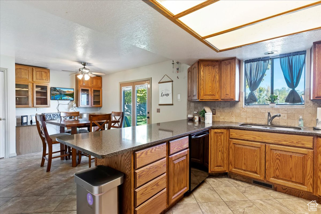 Kitchen featuring dishwasher, decorative backsplash, kitchen peninsula, and a textured ceiling