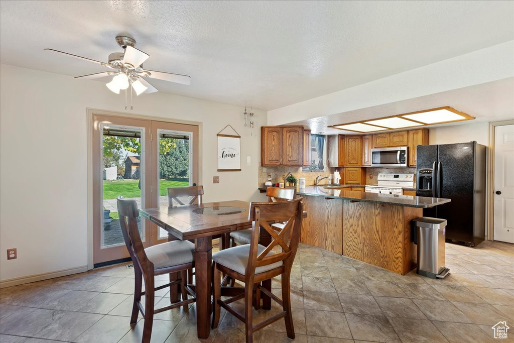 Tiled dining area with a textured ceiling, sink, and ceiling fan