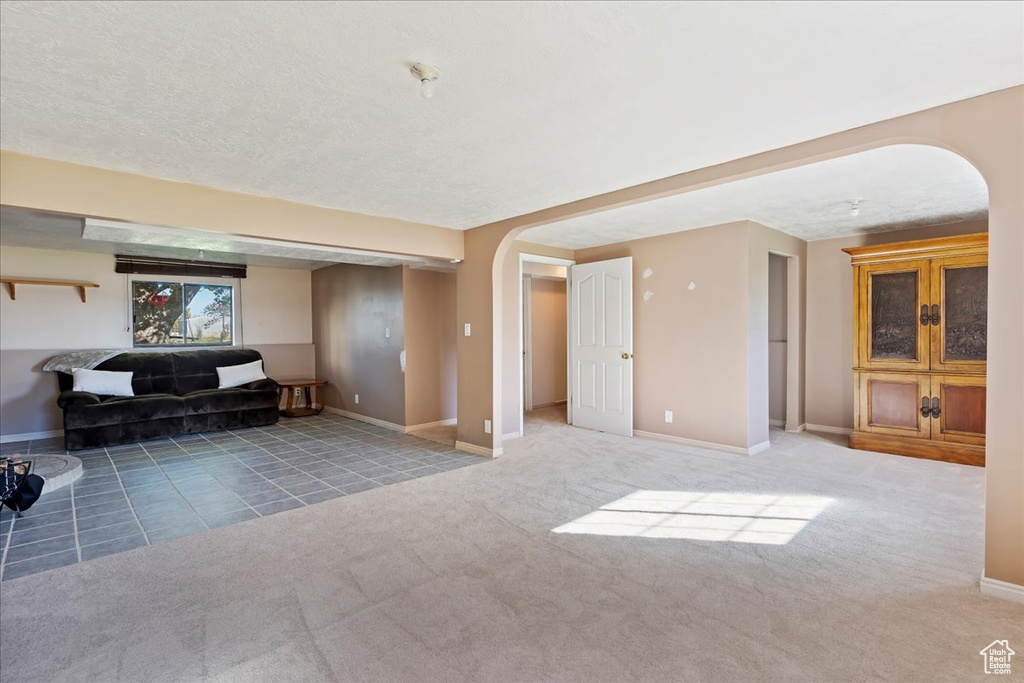 Unfurnished living room featuring carpet flooring and a textured ceiling