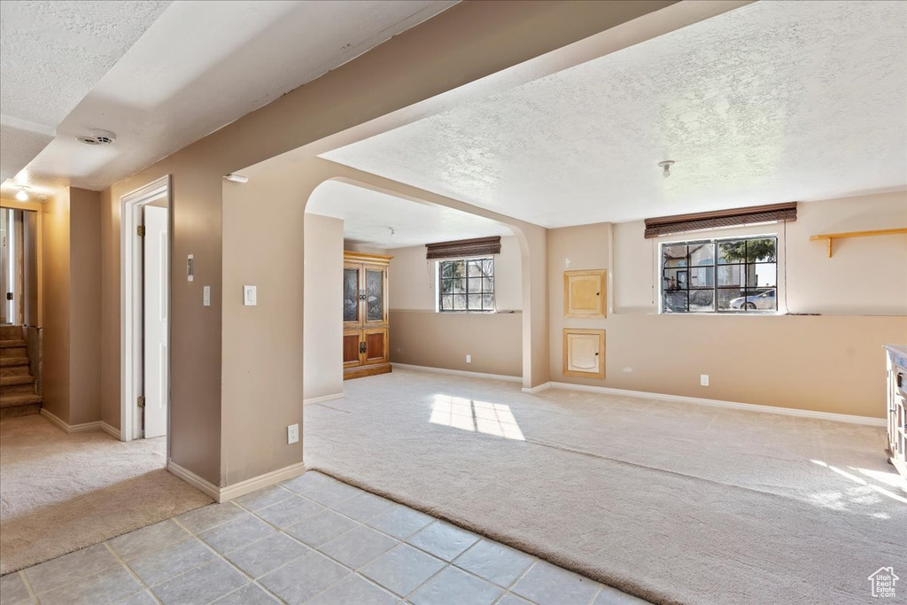 Unfurnished living room with a wealth of natural light, a textured ceiling, and light colored carpet