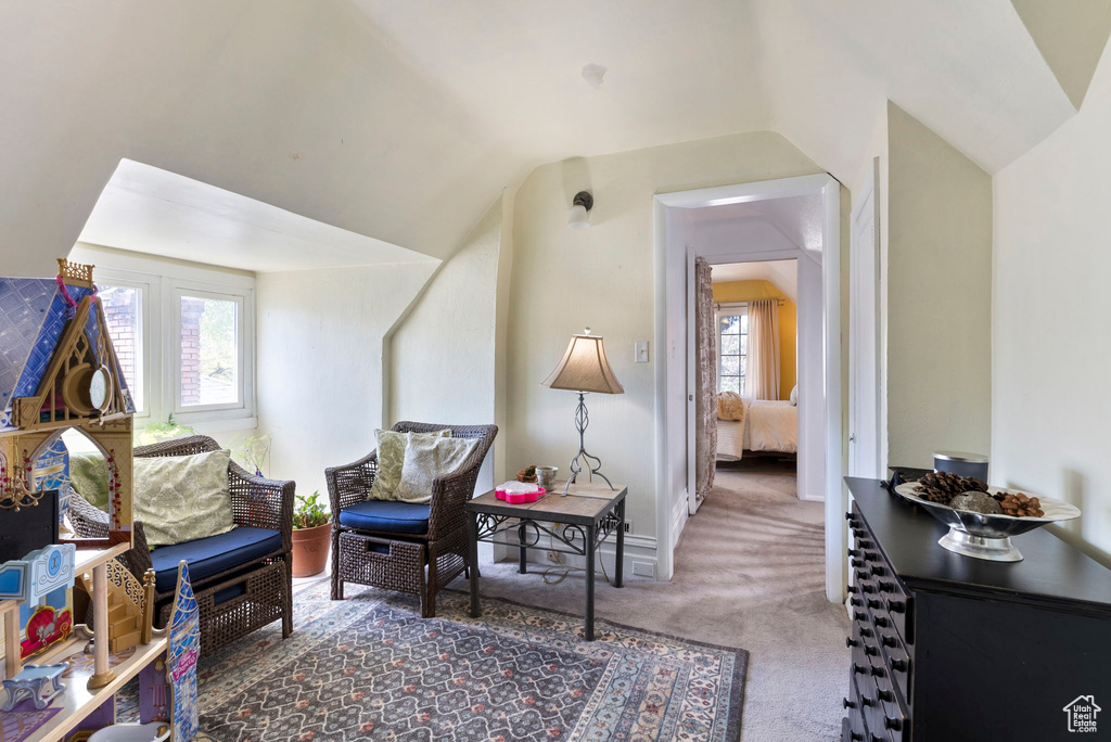 Living area featuring a healthy amount of sunlight, carpet flooring, and vaulted ceiling