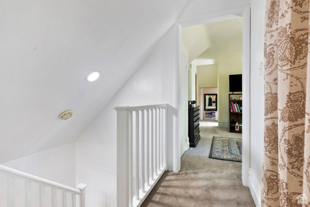 Hallway featuring lofted ceiling and light colored carpet