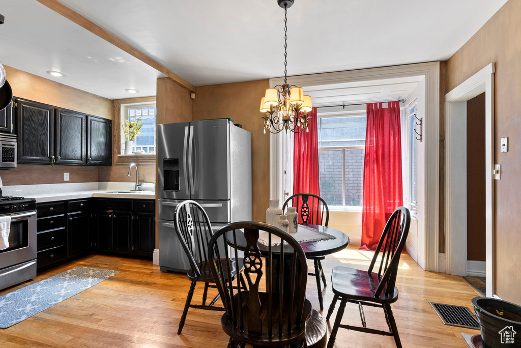 Kitchen with an inviting chandelier, stainless steel appliances, sink, light hardwood / wood-style floors, and decorative light fixtures