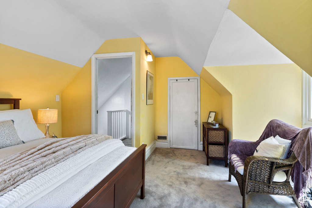 Bedroom featuring radiator, light carpet, and lofted ceiling