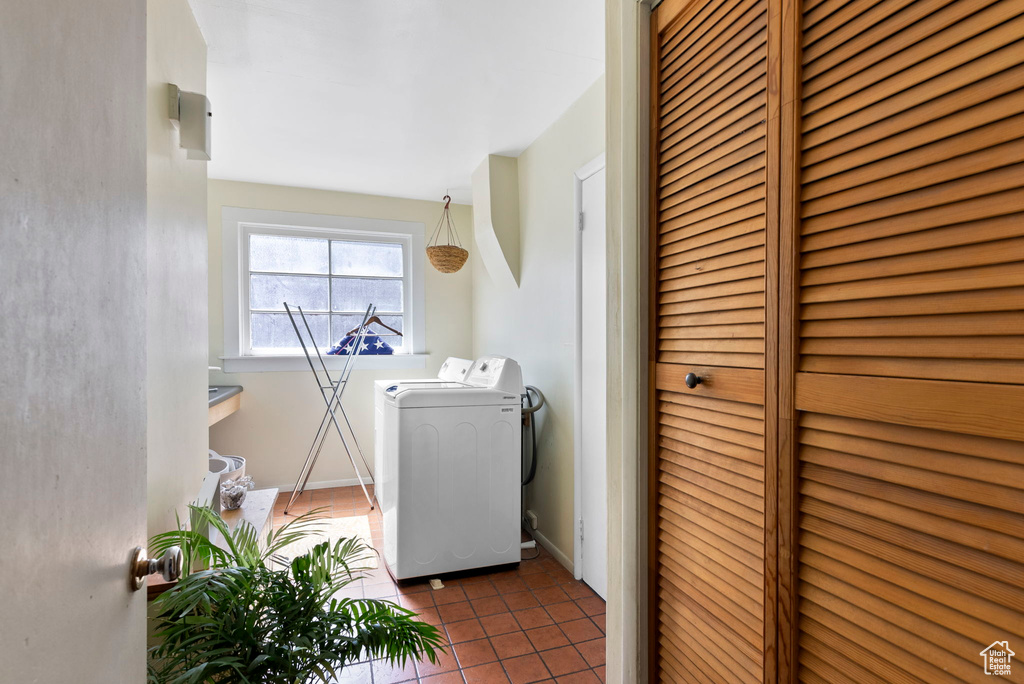 Clothes washing area with dark tile patterned flooring and washer and dryer