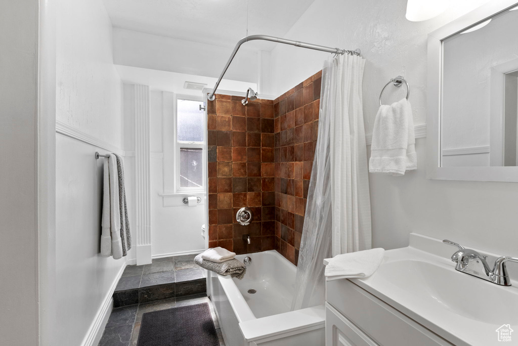 Bathroom with vanity, shower / tub combo with curtain, and tile patterned flooring