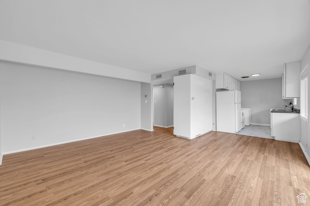 Unfurnished living room featuring light hardwood / wood-style floors and sink