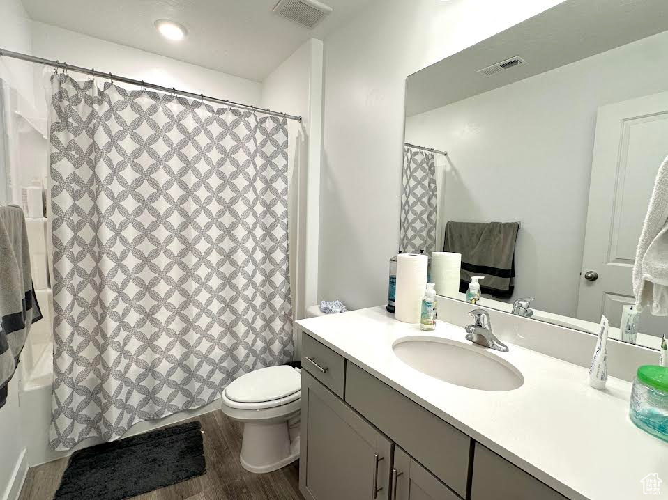 Full bathroom featuring vanity, toilet, wood-type flooring, and shower / tub combo