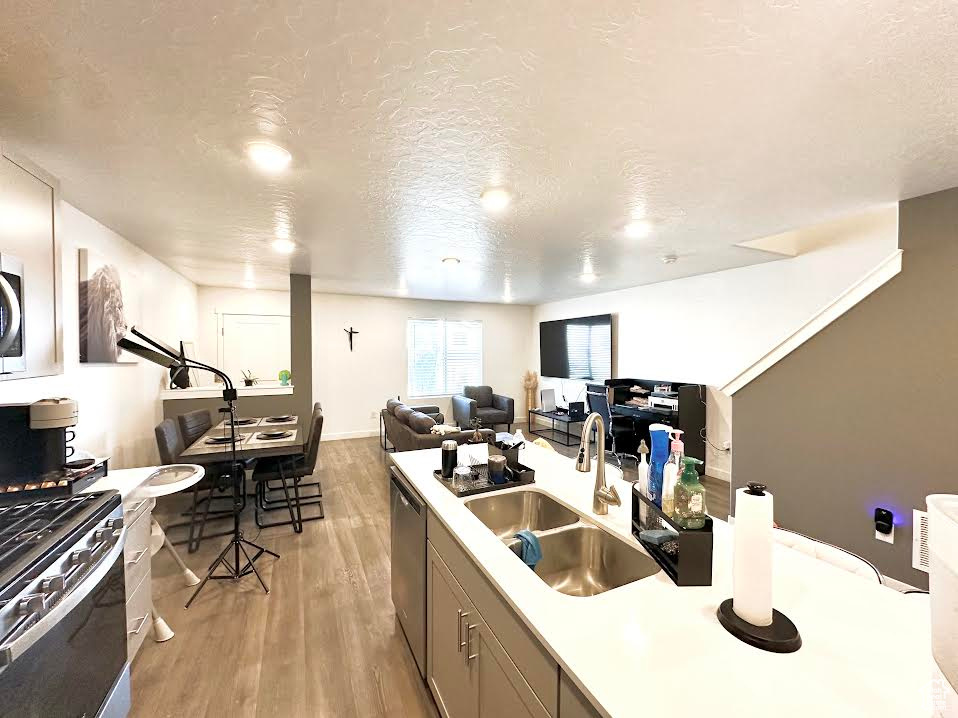 Kitchen featuring sink, appliances with stainless steel finishes, a textured ceiling, and light wood-type flooring