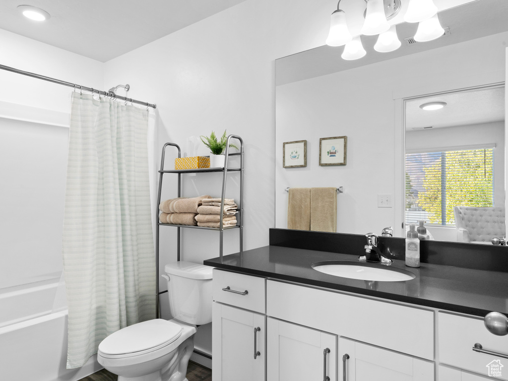 Full bathroom with vanity, shower / bath combo, and toilet