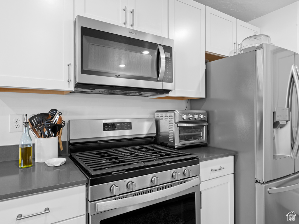 Kitchen with appliances with stainless steel finishes and white cabinetry