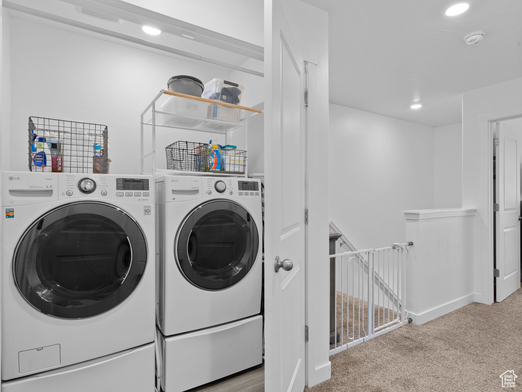 Washroom with light carpet and washer and clothes dryer