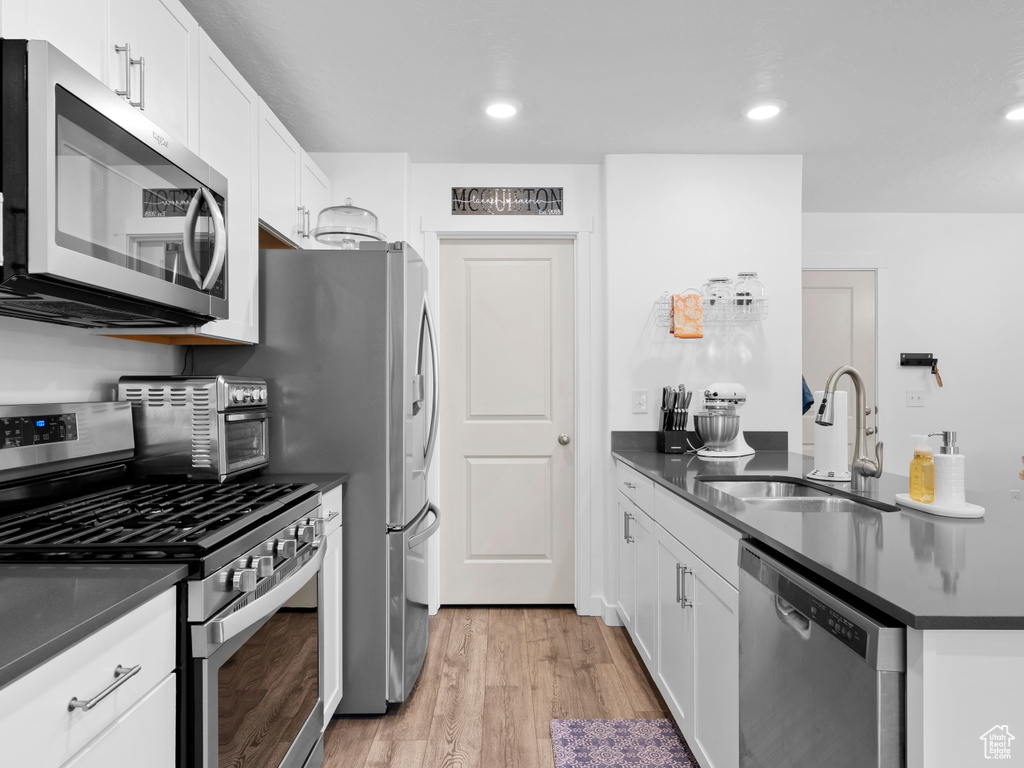 Kitchen featuring white cabinetry, light hardwood / wood-style floors, stainless steel appliances, and sink