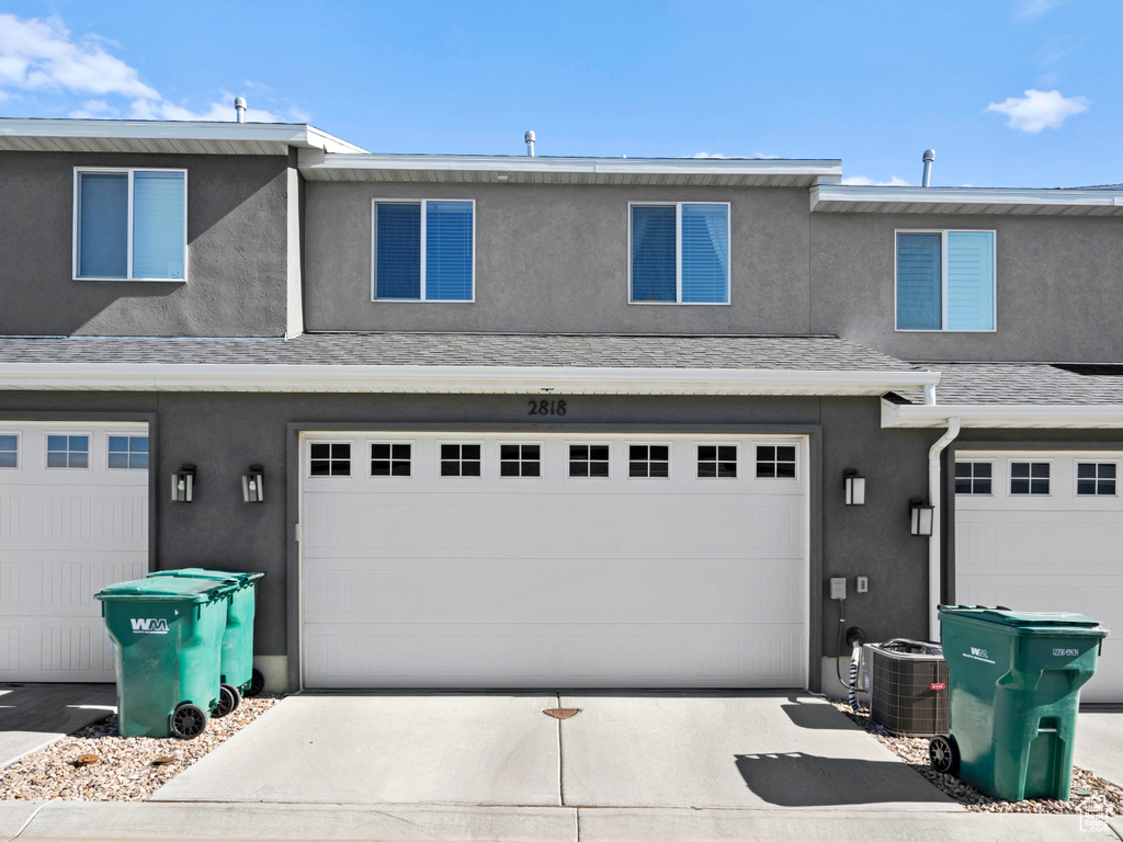 View of front of property featuring central air condition unit and a garage