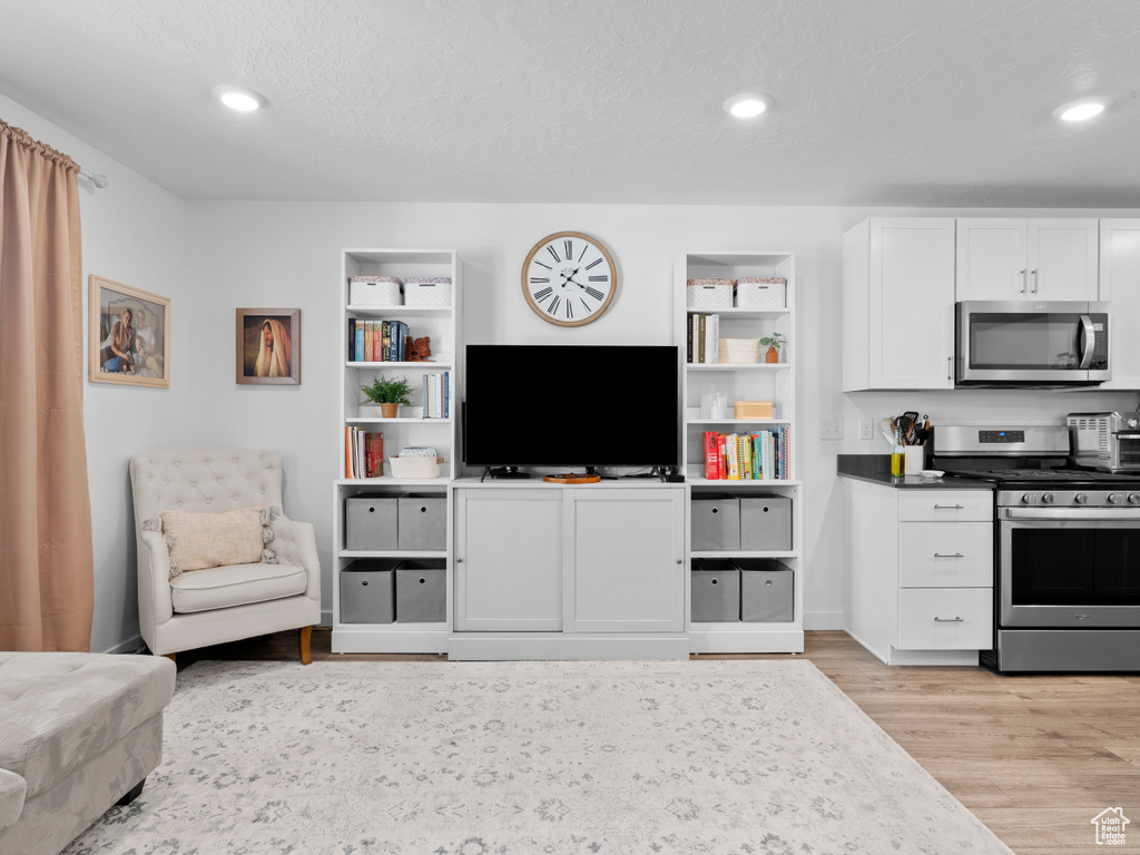 Interior space featuring appliances with stainless steel finishes, white cabinets, a textured ceiling, and light wood-type flooring